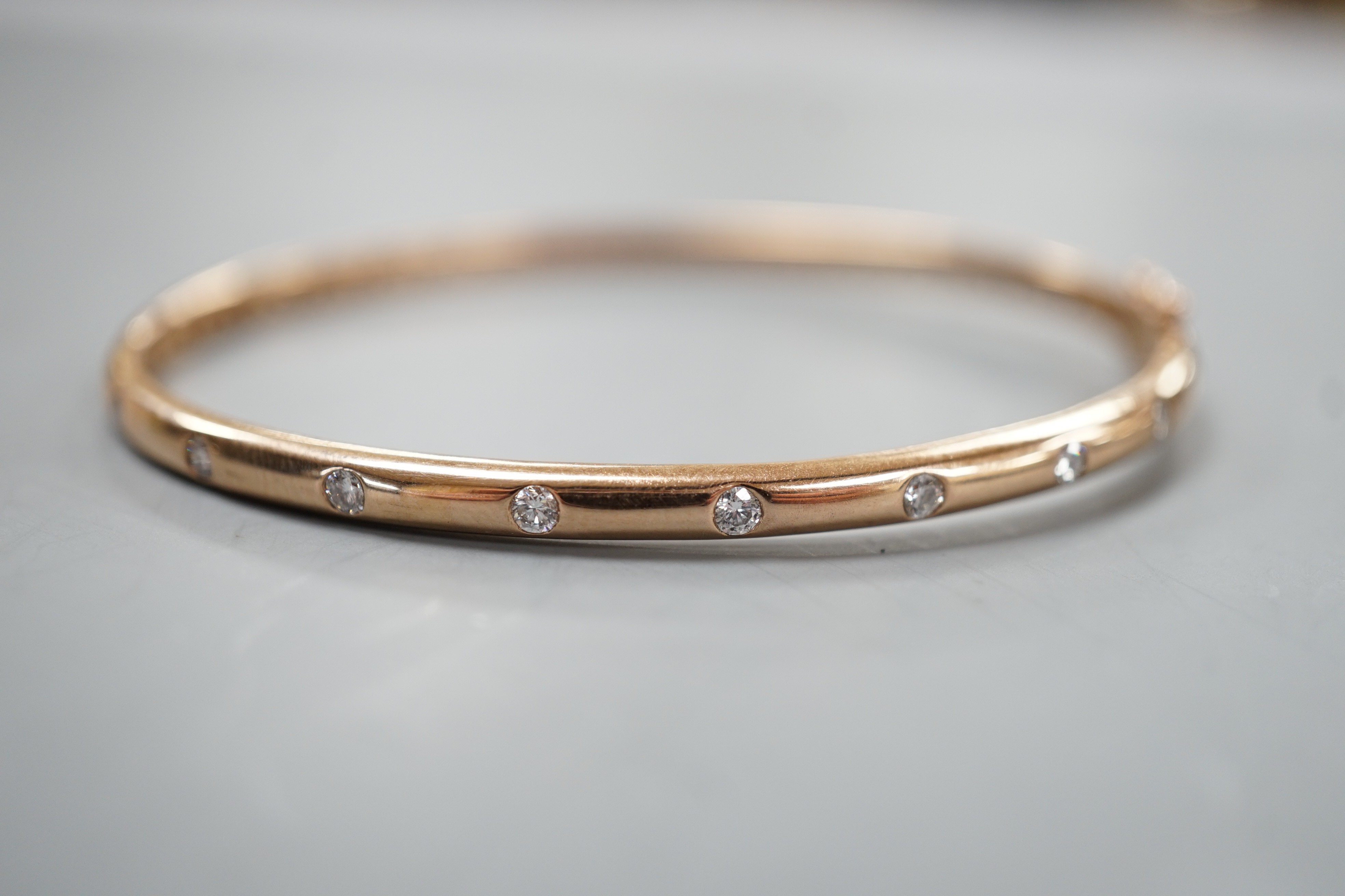 A modern 9k and nine stone gypsy set diamond hinged bangle, interior diameter 60mm, gross weight 9.3 grams.